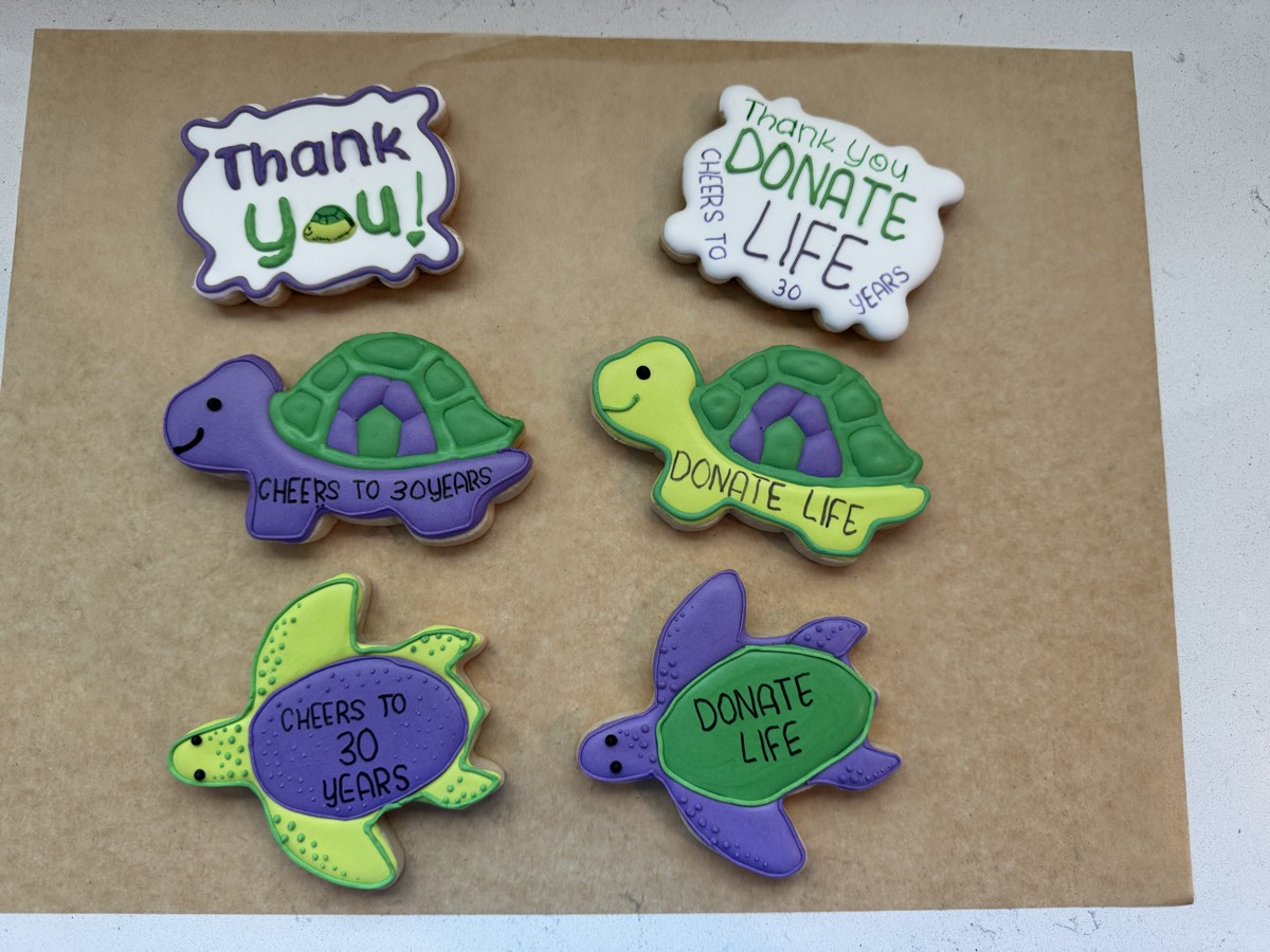 Purple and green sea turtle decorated sugar cookies reading "Cheers to 30 Years" and "Donate Life" for an organ donation awareness event
