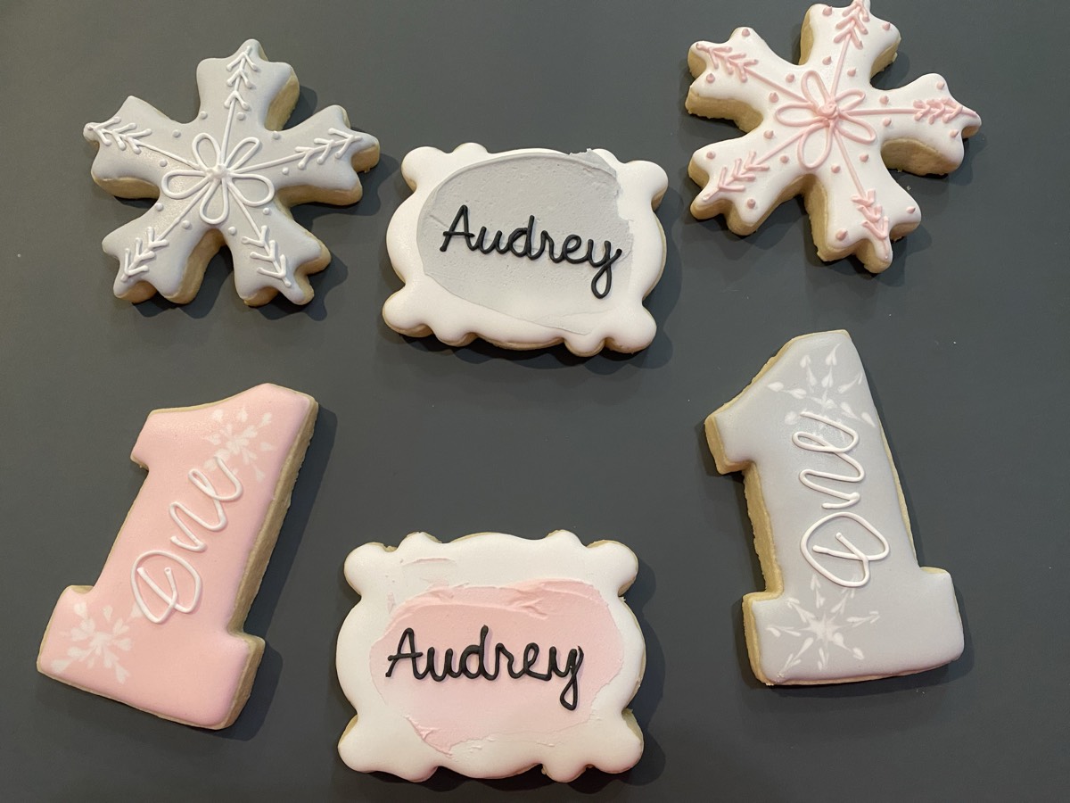 A pink and white first-birthday cookie set with winter snowflake designs
