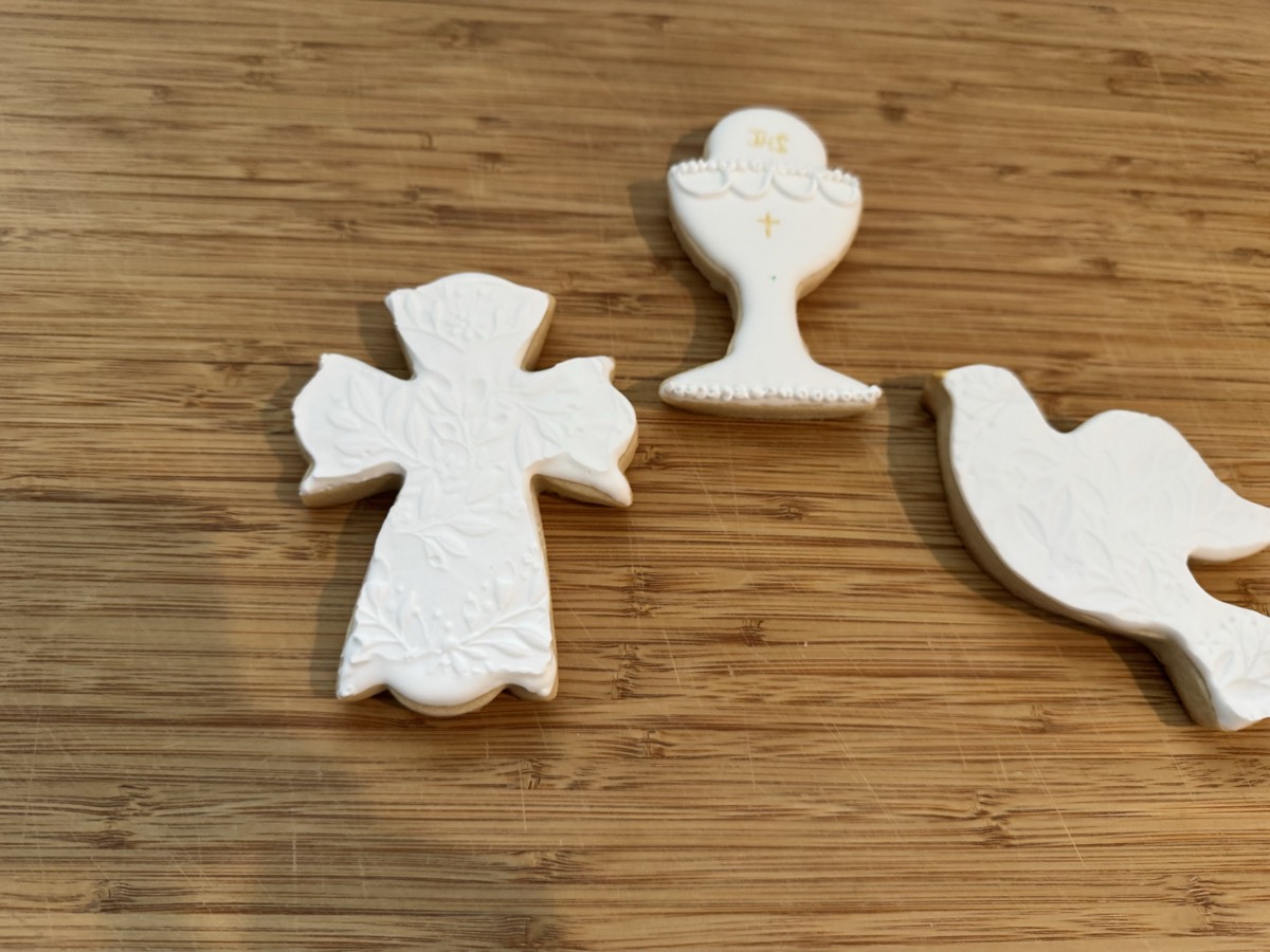 A second First Communion cookie set with an embossed cross, chalice, and dove in white icing with gold accents