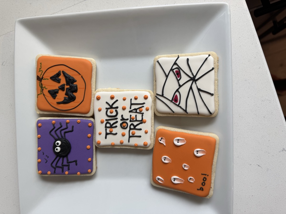 Halloween decorated sugar cookie squares featuring a spider, a jack-o'-lantern, "Trick or Treat" lettering, ghosts, and a mummy