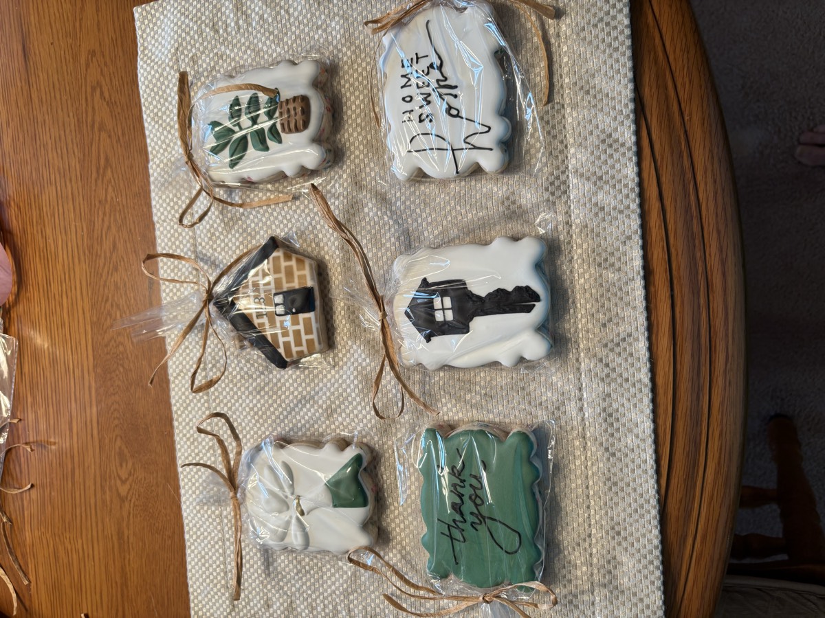 Individually wrapped housewarming decorated sugar cookies: a wrapped gift, a brick house, a potted plant, a "thank you" cookie, a house key, and a "Home Sweet Home" cookie