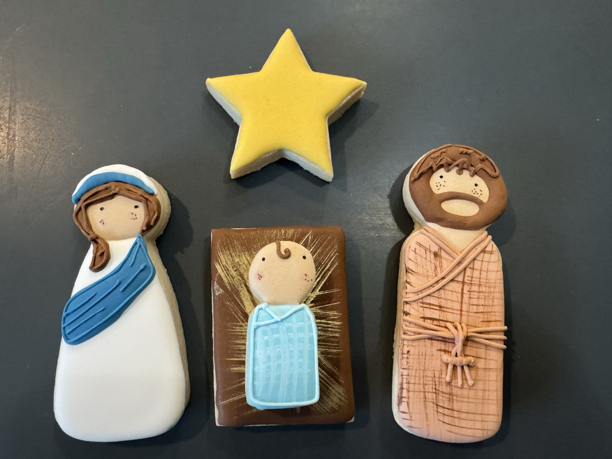 Mary, baby Jesus in a manger, and Joseph decorated sugar cookies with a gold star, in soft blues, whites, and browns