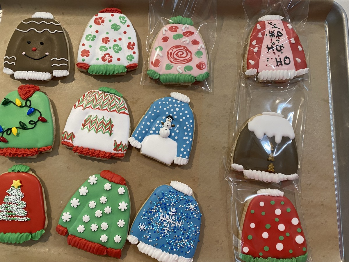 Ugly Christmas sweater decorated sugar cookies with trees, string lights, snowflakes, polka dots, and a gingerbread face design