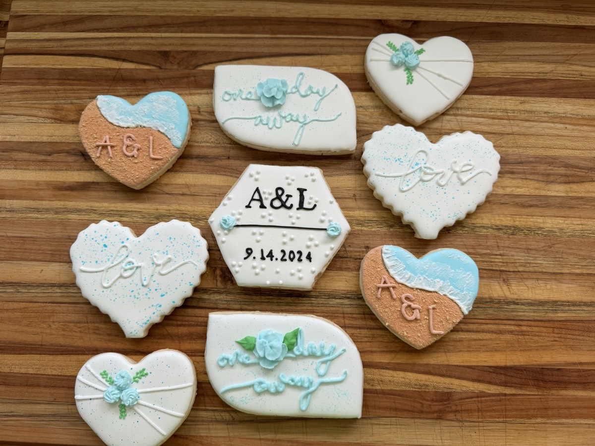 Cream, tan, and blue wedding decorated sugar cookies with hearts, the couple's initials, and a hexagon cookie with the wedding date