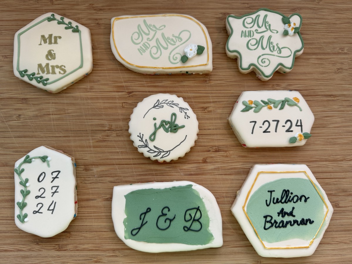 Sage green and white wedding decorated sugar cookies reading "Mr & Mrs", the couple's initials, and the wedding date, with vine and floral details