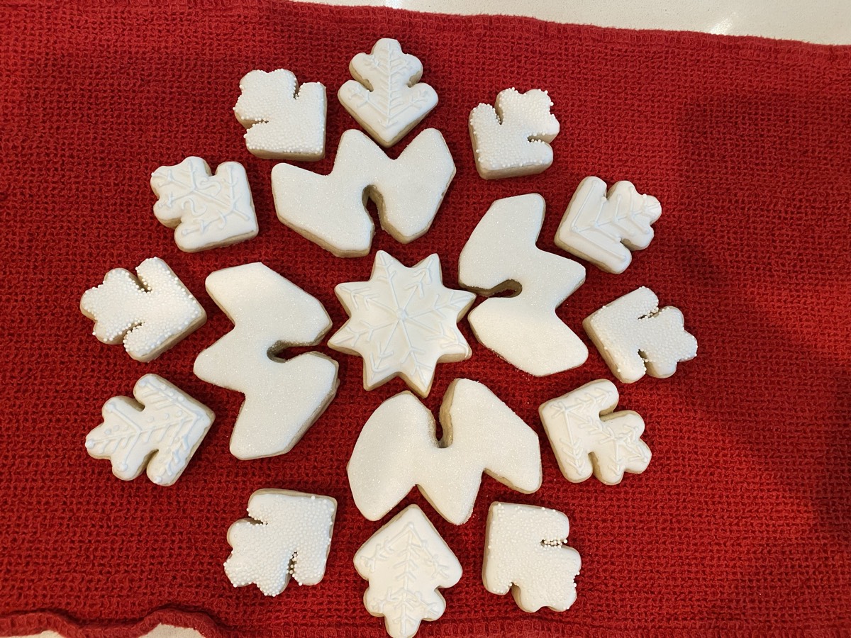 White embossed snowflake and leaf shaped decorated sugar cookies arranged in a wreath pattern