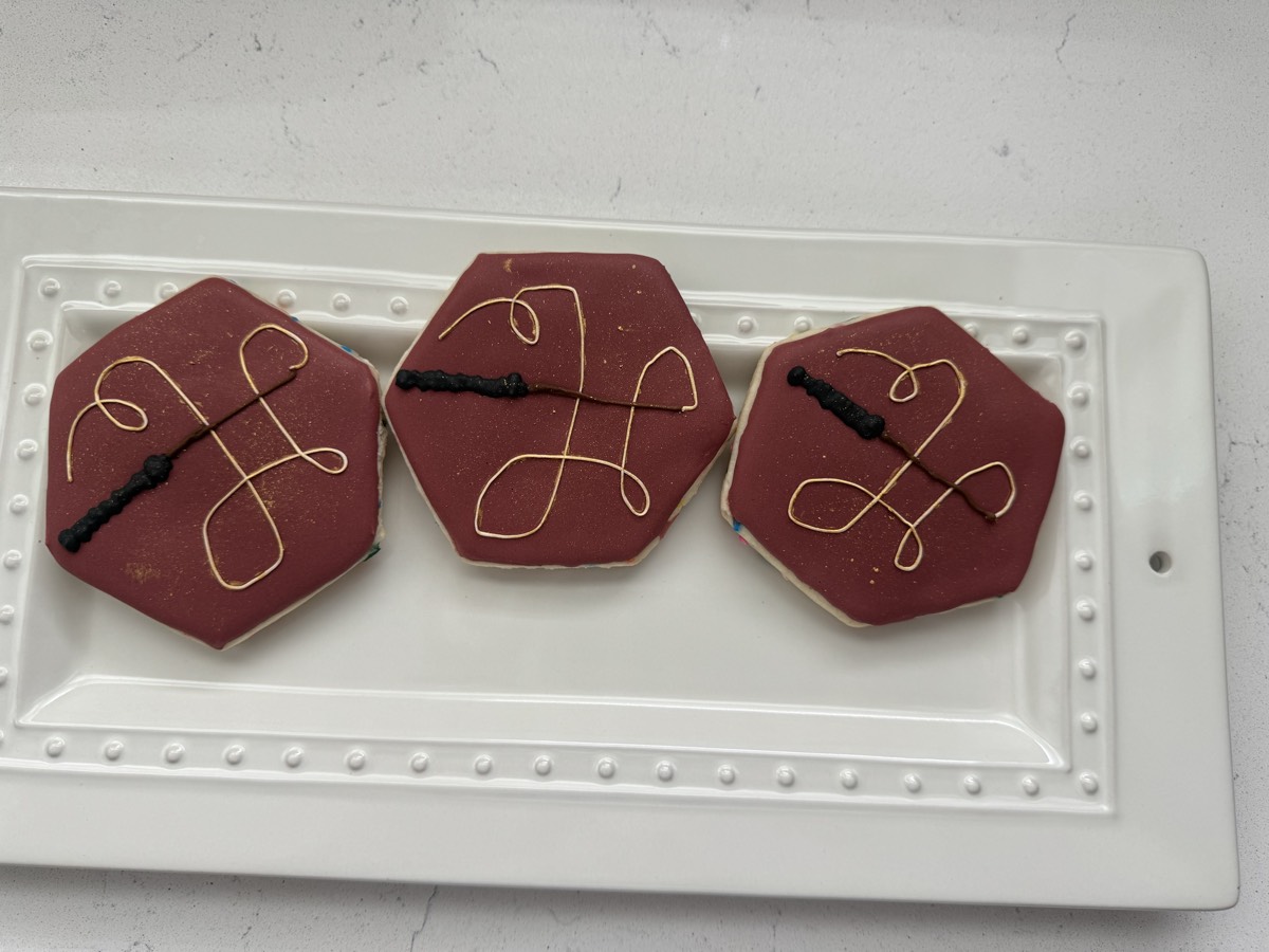 Maroon and gold hexagon decorated sugar cookies with a wand design